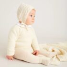 Baby sitting on ivory cashmere knit blanket with matching knitwear