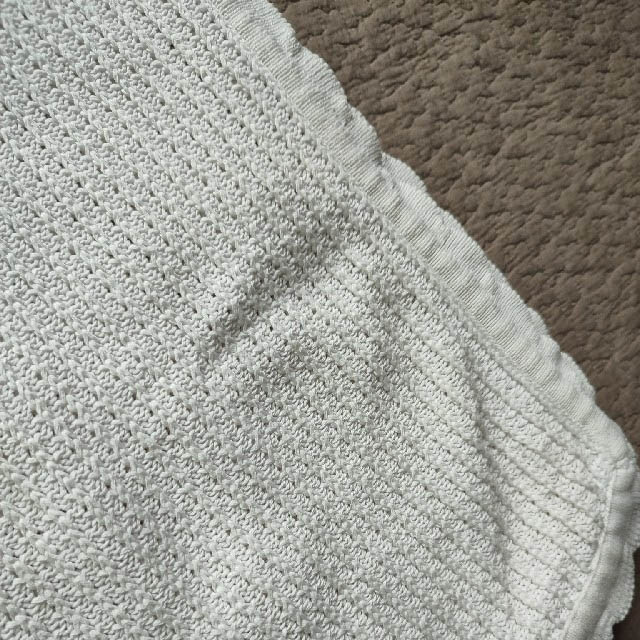 Baby wrapped in white cotton baby knit blanket