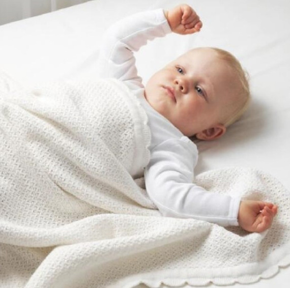Cotton baby knit blanket rolled up showing scallop edge detail