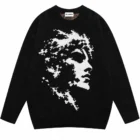 Black cotton jacquard knit sweater laid flat showing the knitted portrait pattern on the front