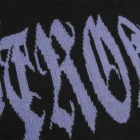 Close-up of the light grey jacquard lettering stitch structure knitted in black, with a laddered hole above