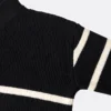 Close-up of a black knitted sweater with cream stripes, showing ribbed knit texture, shoulder seam and sleeve details