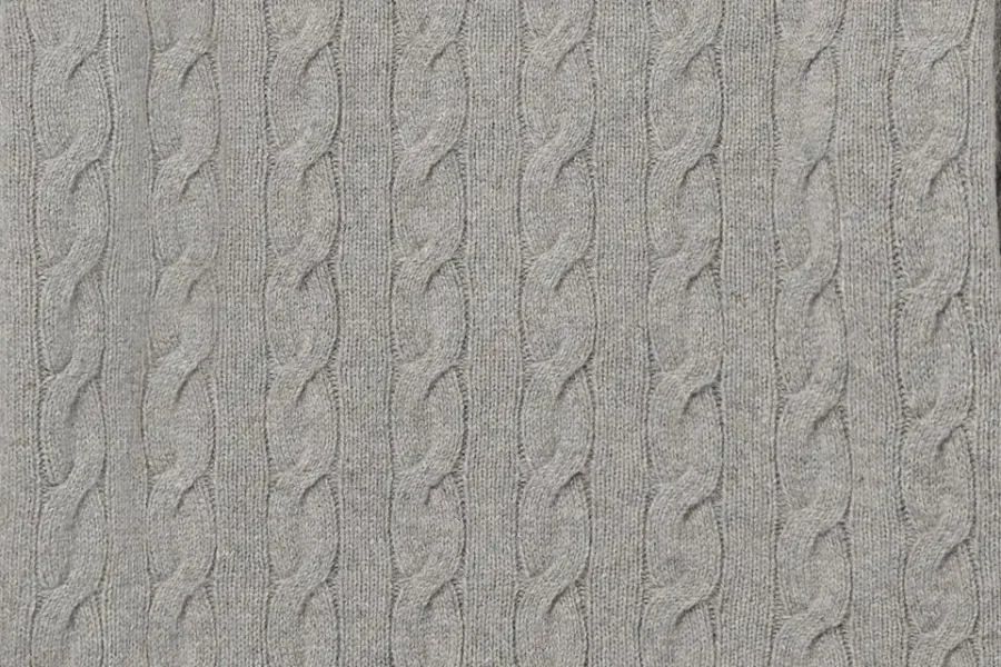 Close-up of gray knitted fabric with repeating vertical cable patterns.