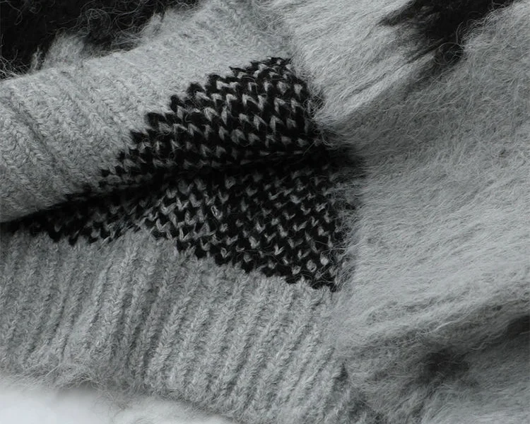 Close-up of a gray and black fuzzy knitted sweater showing its soft, hairy surface and textured knit pattern.