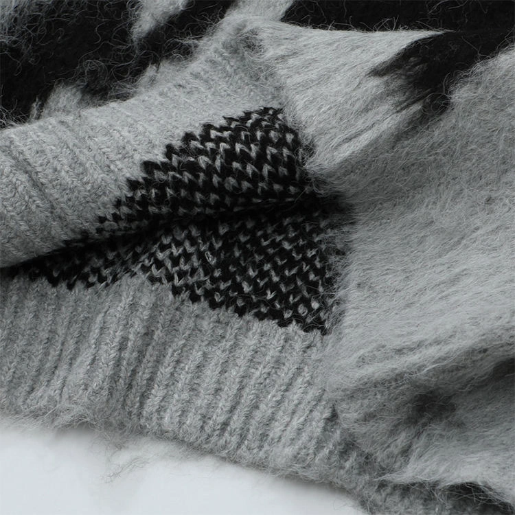 Close-up of a gray and black fuzzy knitted sweater showing its soft, hairy surface and textured knit pattern.